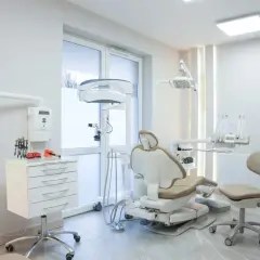 Nowoczesny gabinet stomatologiczny z fotelem dentystycznym i sprzętem medycznym.
