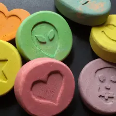 Kolorowe tabletki z symbolami: serce, gwiazda, kosmita, uśmiech, czaszka. To mogą być tabletki MDMA.