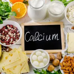 Talerzyk z serem, fasolą, orzechami i mlekiem. Tabliczka z napisem "Calcium" przypomina o ważnym składniku odżywczym.