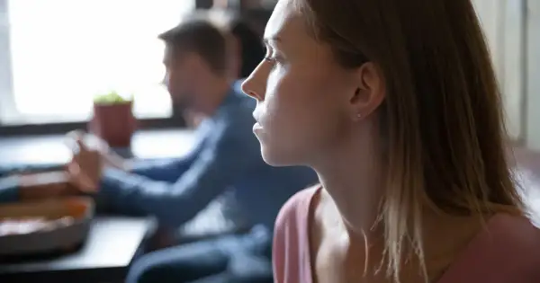 Kobieta z zamyśloną miną, być może zmagająca się z myślami typowymi dla osobowości anankastycznej, siedzi przy stole.