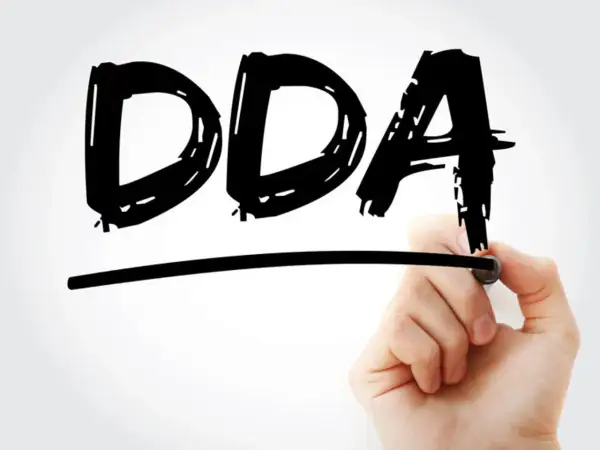 Ręka pisze markerem "DDA", symbolizując objawy dorosłych dzieci alkoholików.