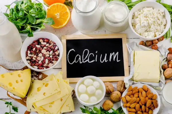 Talerzyk z serem, fasolą, orzechami i mlekiem. Tabliczka z napisem "Calcium" przypomina o ważnym składniku odżywczym.